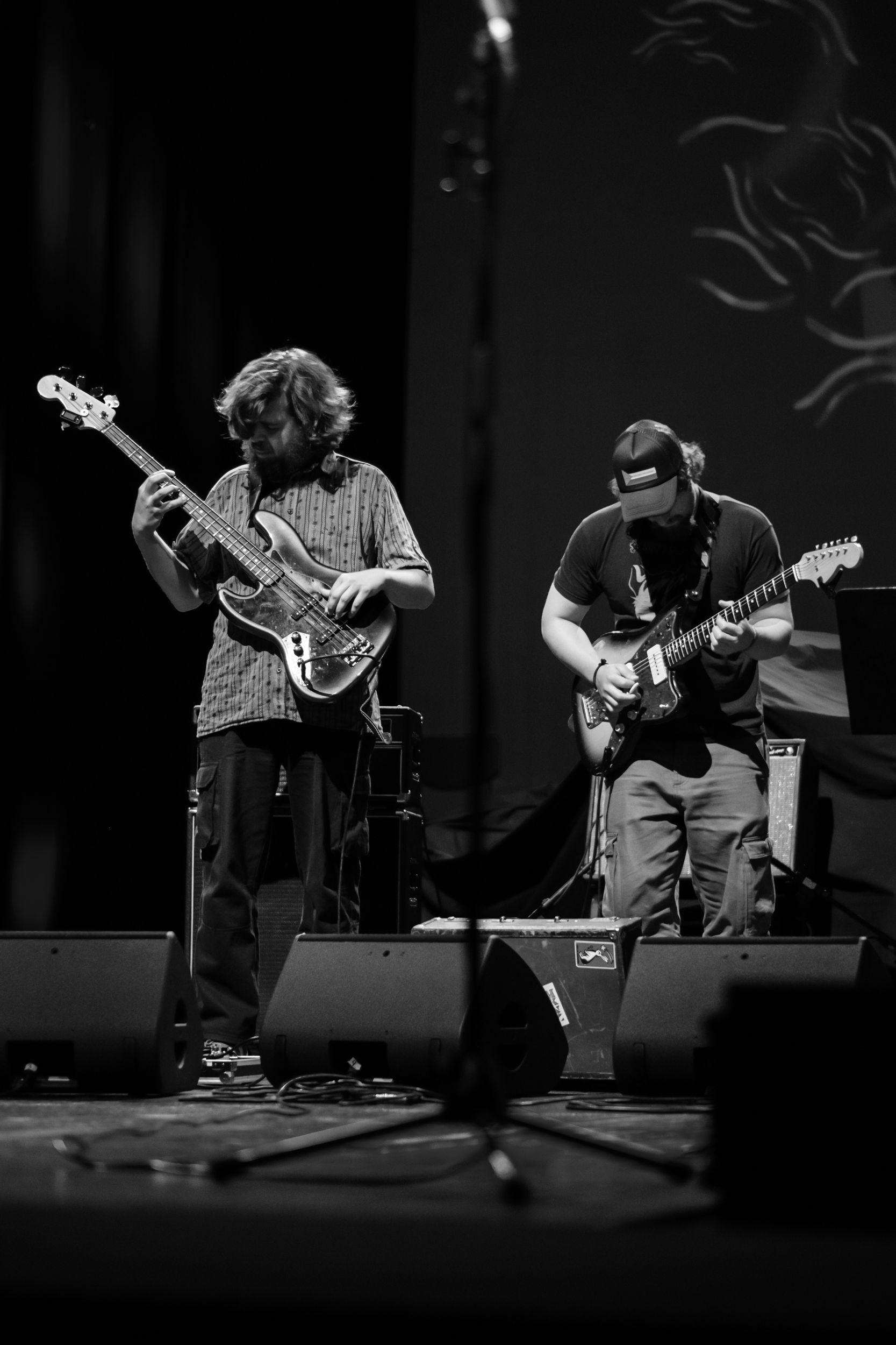 Two string-instrument players perform on stage in a vertical photograph.