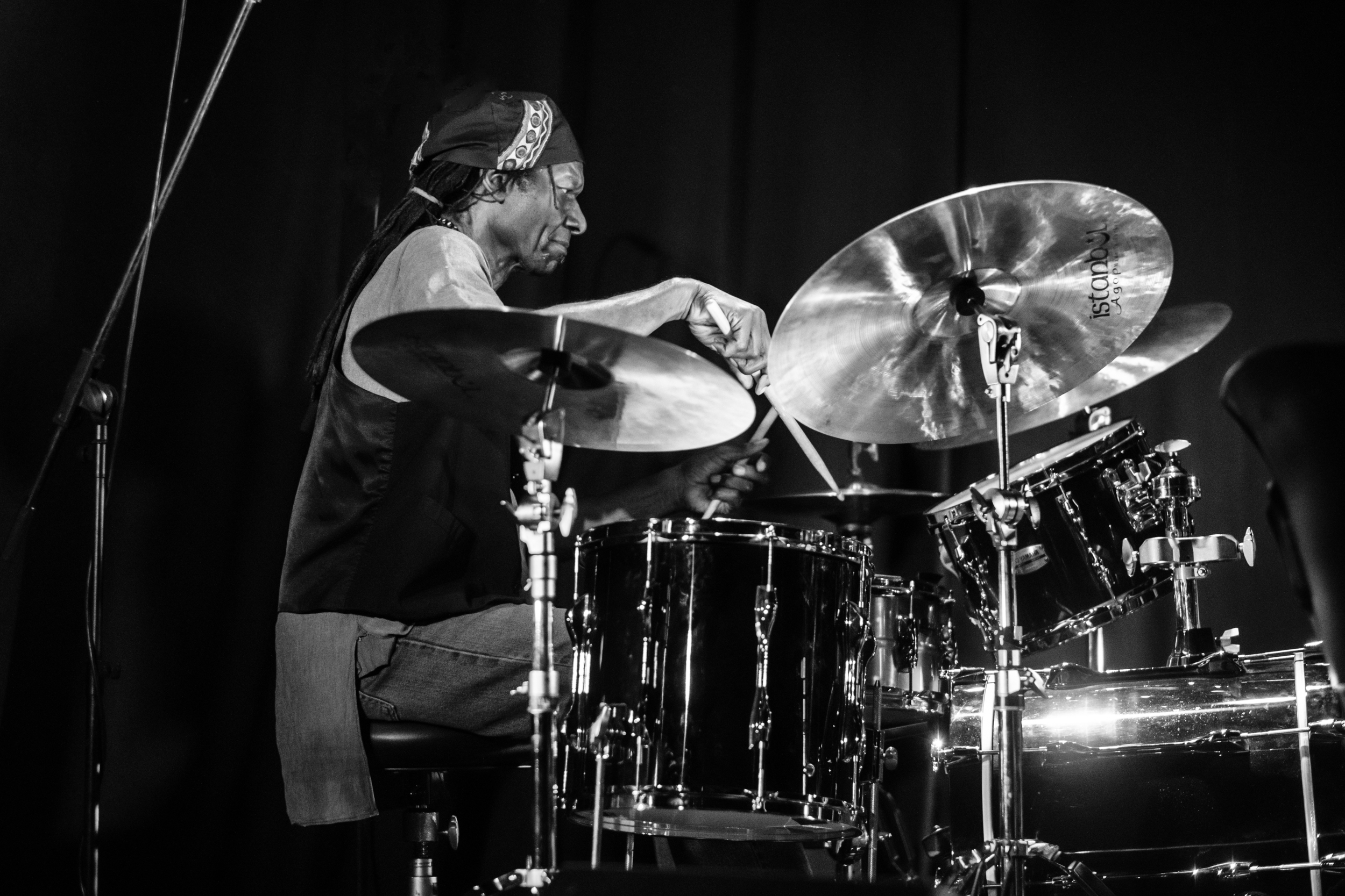 A drummer reaches toward the cymbals of a drum kit.