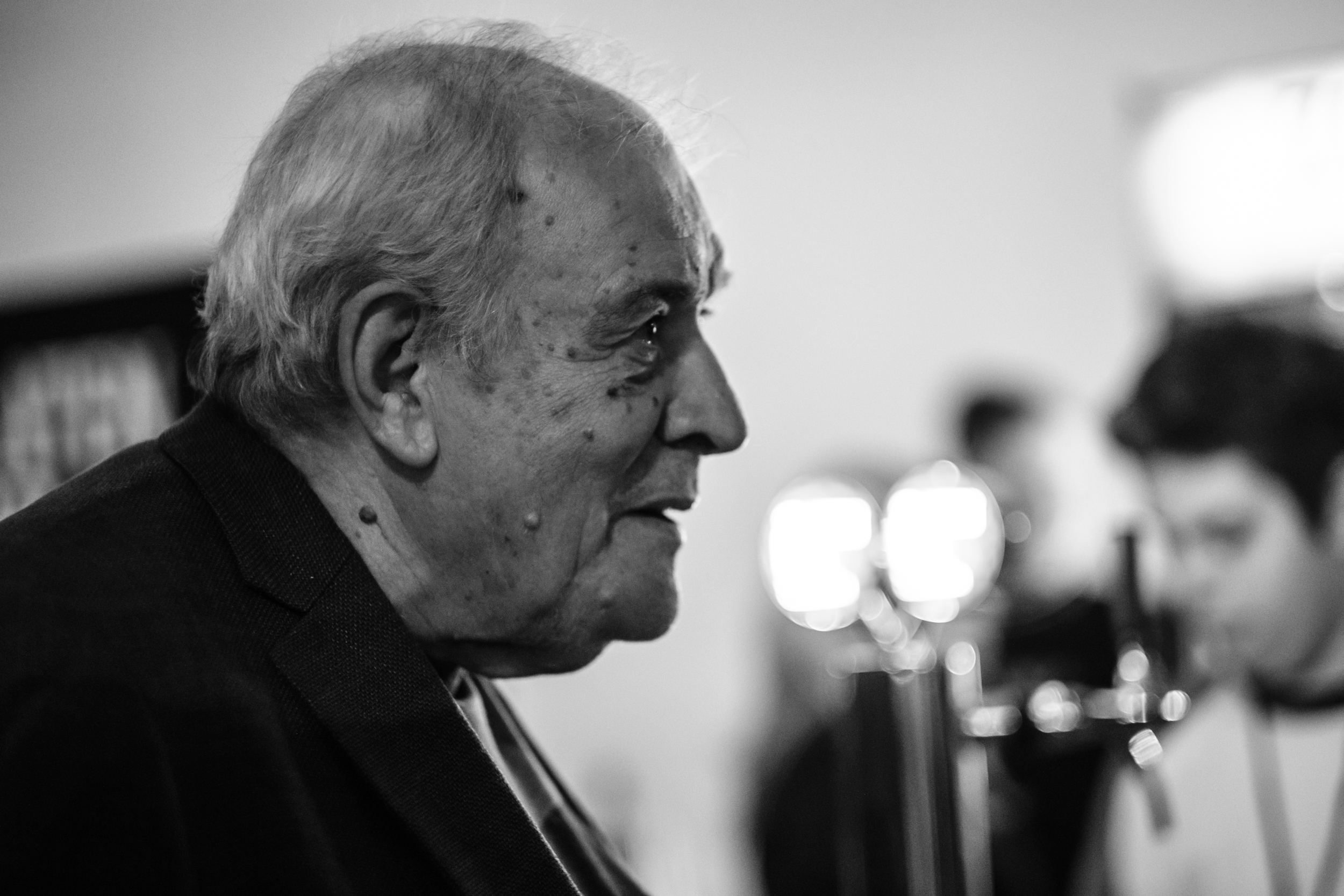 Close side profile of an older man among festival visitors.