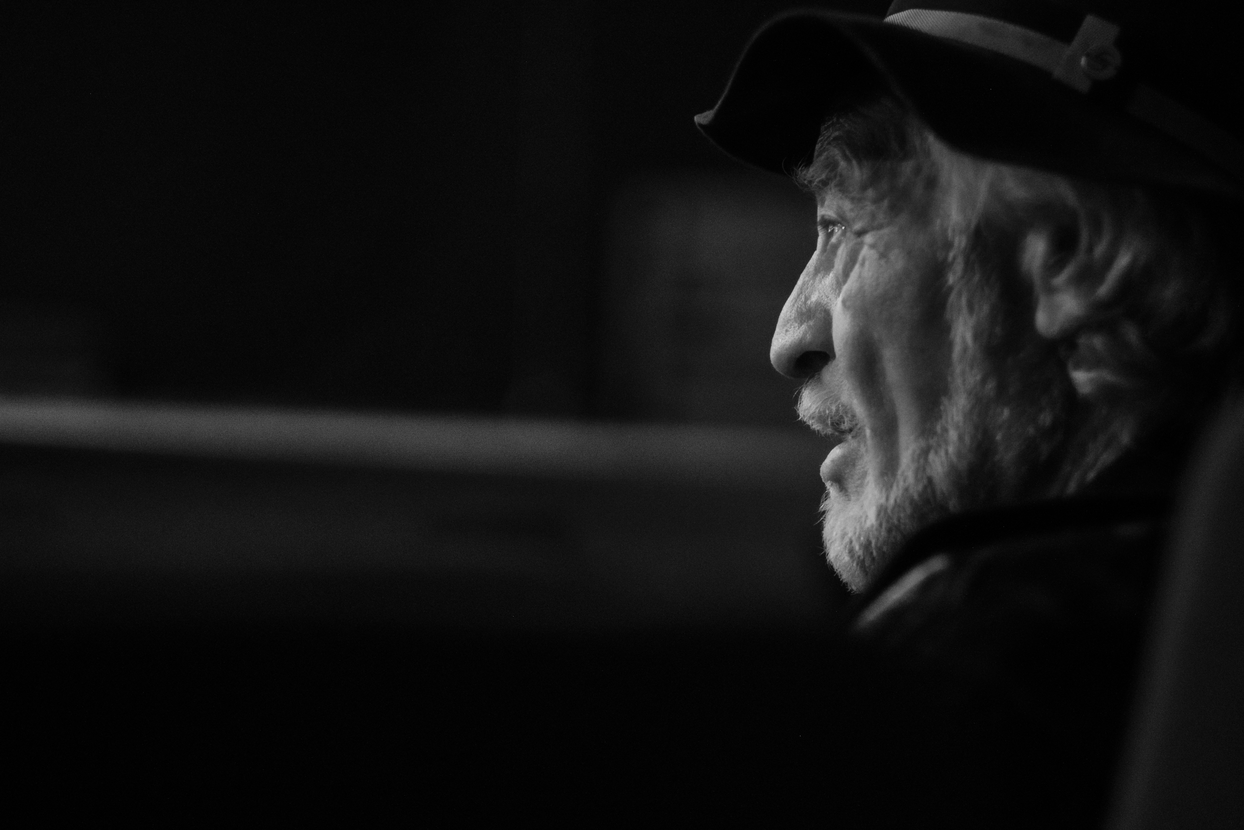 Side profile of a man in a cap against a dark interior.