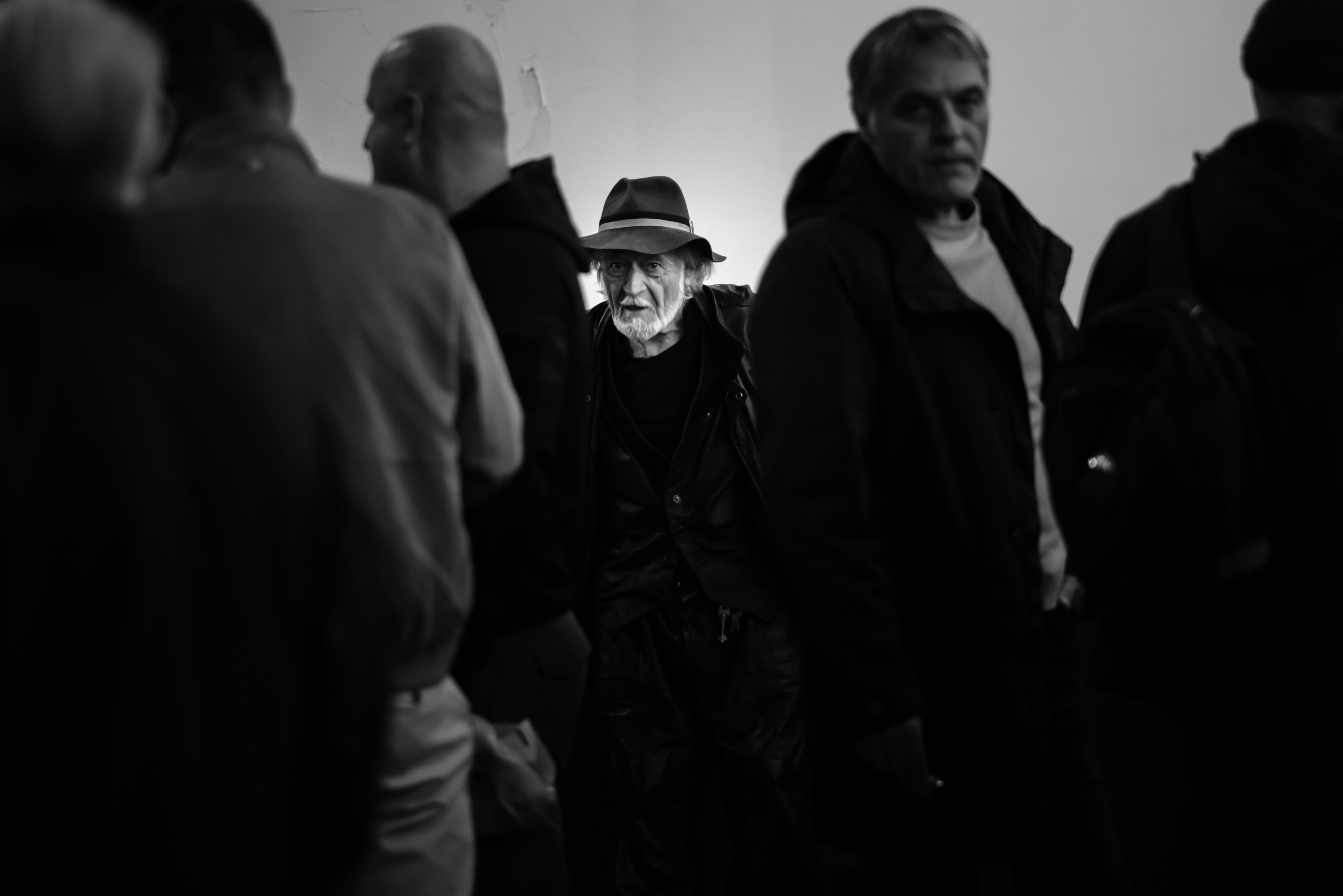 A man wearing a brimmed hat stands among other festival visitors.